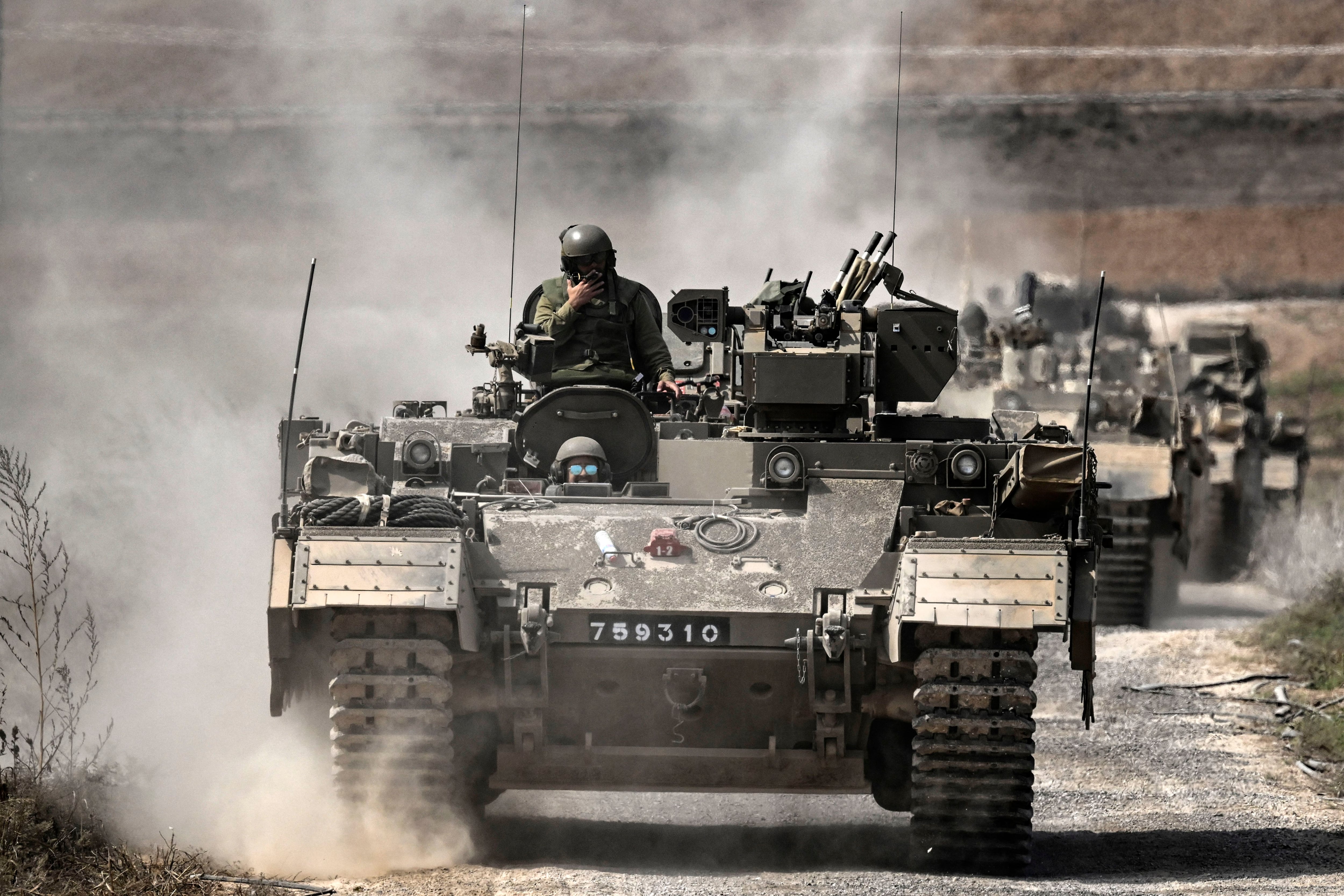 Israeli armored personnel carriers (APCs) move in column near the Gaza border on October 14, 2023. (Photo by Aris MESSINIS/AFP).