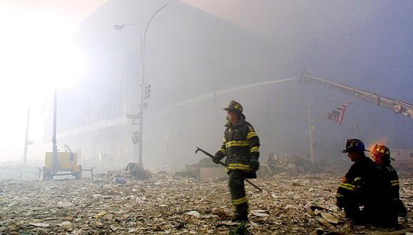 En esta foto de archivo, un bombero camina entre los escombros de las torres gemelas del World Trade Center mientras una bandera estadounidense cuelga de un semáforo el 11 de septiembre de 2001 en Nueva York. (Foto: DOUG KANTER / AFP)