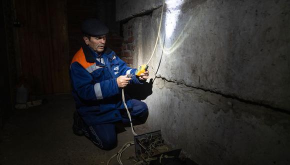 Alexander, un residente local, arregla el suministro de electricidad en el sótano de un edificio dañado donde vive en la ciudad de Lyman, región de Donetsk, el 10 de noviembre de 2022, en medio de la invasión rusa de Ucrania. (Foto de Ihor Tkachov / AFP)