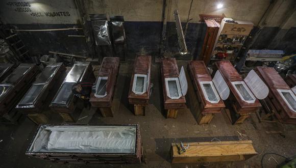 El migrante peruano dedicado a hacer ataúdes César Ambrosio, termina los detalles de una línea de producción en la funeraria Bergut en Santiago, Chile, el jueves 18 de junio de 2020. (AP Foto/Esteban Felix).