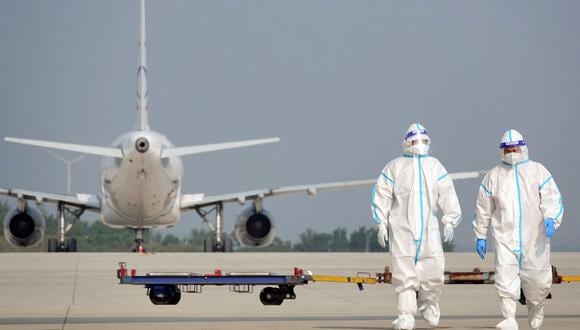 Esta foto tomada el 18 de septiembre de 2022 muestra al personal de tierra de aviación con equipo de protección personal (EPP) trabajando en un avión que voló desde el extranjero en el aeropuerto de Yantai, en la provincia oriental china de Shandong. (Foto de AFP)