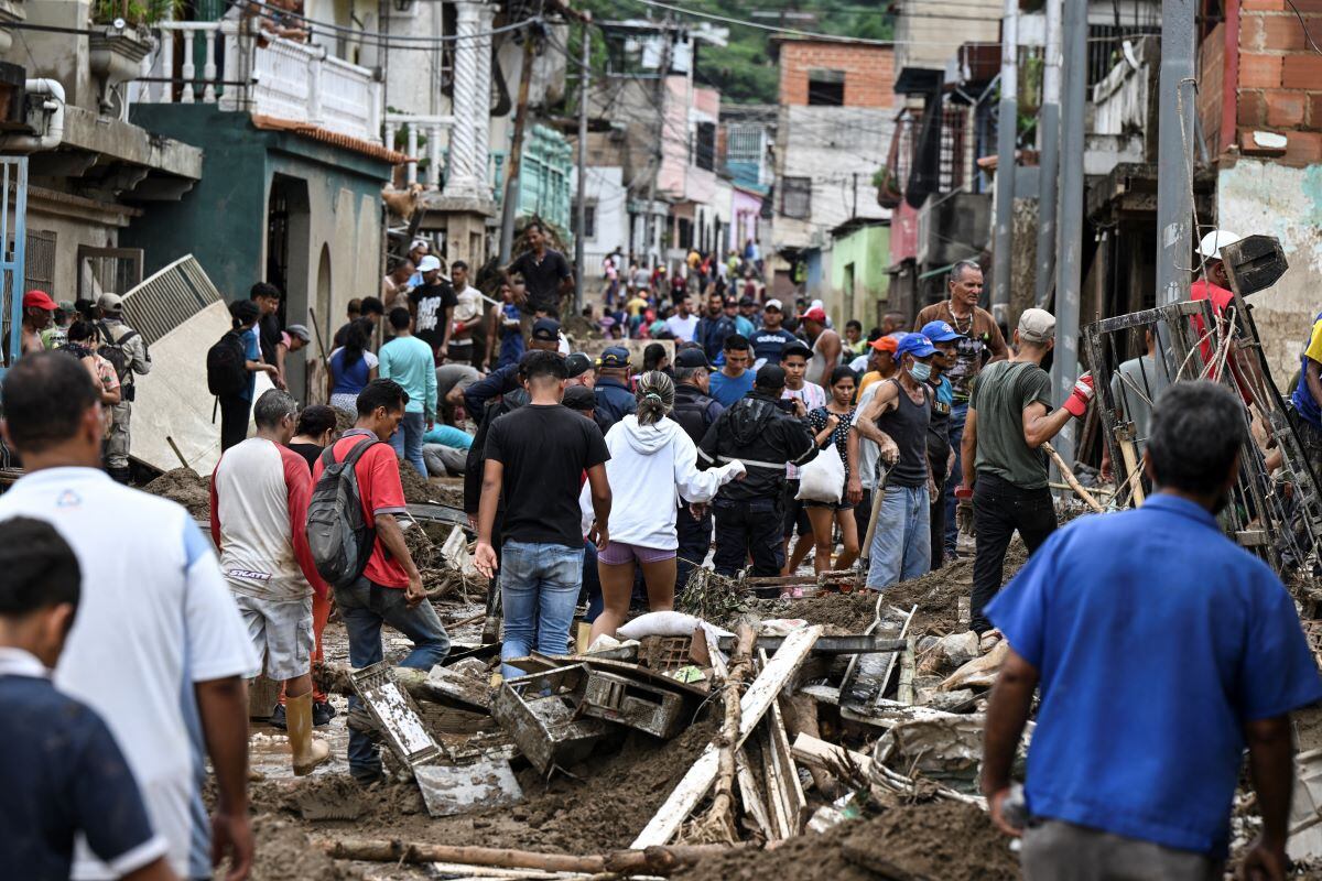 Residents walk among the rubble of houses destroyed by a landslide during heavy rains in Las Tejerias, Aragua state, Venezuela, on October 9, 2022. (Yuri CORTEZ / AFP)