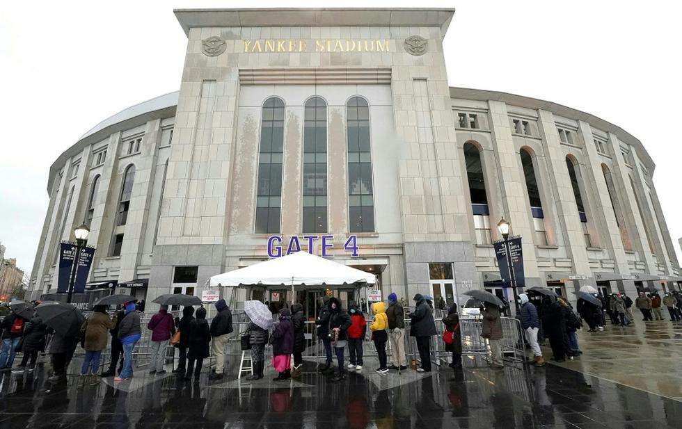 Envueltos en gruesos abrigos, desafiando el frío y la lluvia, centenares comenzaron a vacunarse contra el COVID-19 en el icónico estadio de los Yankees en el Bronx, el distrito más golpeado por el virus en Nueva York y uno de los más pobres de Estados Unidos, donde la mayoría de la población es negra y latina. "Esto es escoger entre la vida y la muerte", dijo a la AFP Inés Figueroa, una puertorriqueña de 64 años que reside en el Bronx, tras recibir la codiciada vacuna en el estadio. Su marido falleció el mes pasado debido a complicaciones tras contraer COVID-19, y Figueroa también lo contrajo, aunque sin síntomas. En la foto, la gente hace cola bajo la lluvia afuera del Yankee Stadium el 5 de febrero de 2021, en Nueva York. (Texto: AFP / Foto: TIMOTHY A. CLARY / AFP)