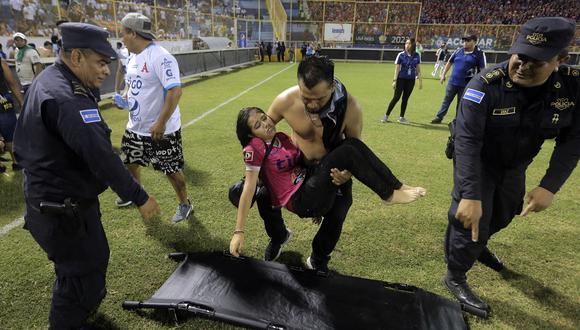 Simpatizantes son ayudados por otros luego de una estampida durante un partido de fútbol entre Alianza y FAS en el estadio Cuscatlán en San Salvador, el 20 de mayo de 2023. (Foto de Milton FLORES / AFP)