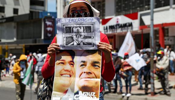 Esta foto de setiembre del 2020 muestra una ciudadana ecuatoriana mientras sostiene un afiche del expresidente Rafael Correa y el candidato Andrés Arauz durante una concentración política en Quito (Ecuador). (Foto: EFE/José Jácome)