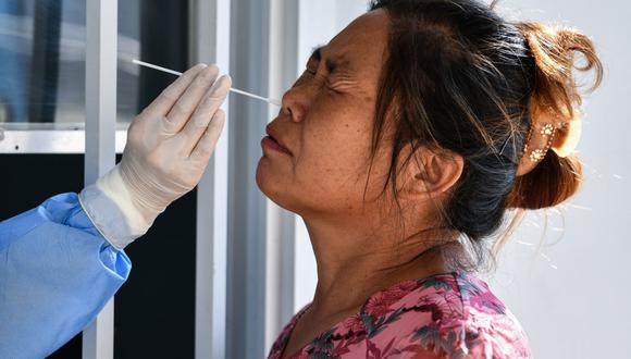 Personal sanitario toma una muestra de hisopo de una mujer para realizar la prueba del coronavirus COVID-19 en el Hospital Tongji, en Wuhan, provincia central de Hubei en China. (Foto de Hector RETAMAL / AFP).