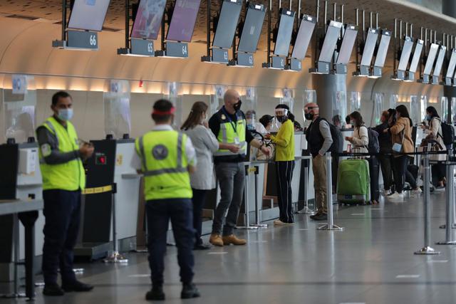 Trabajadores y pasajeros con caretas y máscaras protectoras se ven en la sección de check-in en el Aeropuerto Internacional El Dorado, en medio de la pandemia de coronavirus (COVID-19), en Bogotá, Colombia. (REUTERS/Luisa González).