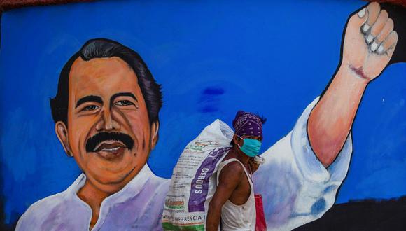 Un hombre que usa mascarilla contra la propagación del nuevo coronavirus pasa frente a un mural que representa al presidente de Nicaragua, Daniel Ortega, en Managua el 9 de abril de 2020. (INTI OCON / AFP).