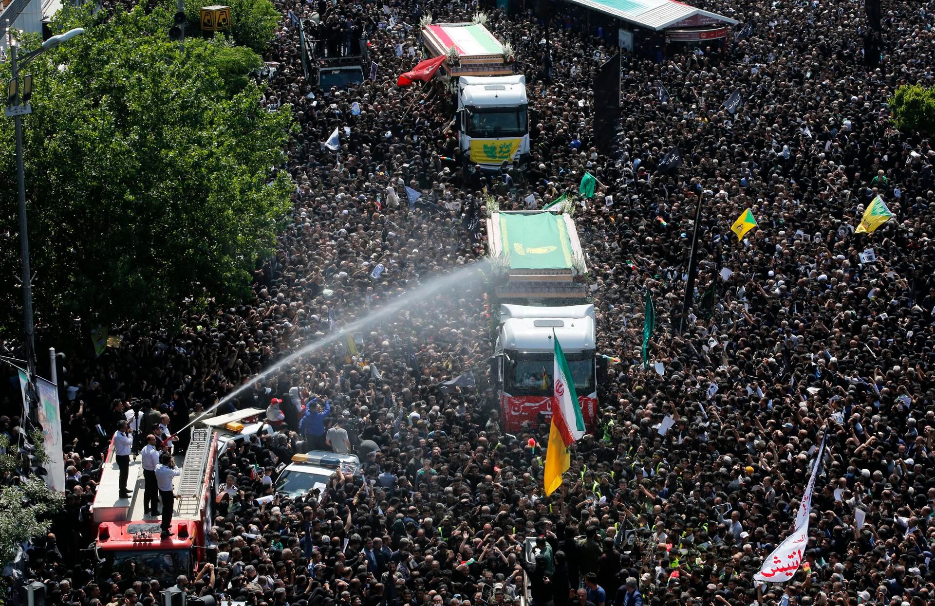 Bomberos iraníes rocían con agua a la multitud en el funeral del presidente Ebrahim Raisi en Teherán, Irán, este miércoles. EFE/ Abedin Taherkenareh