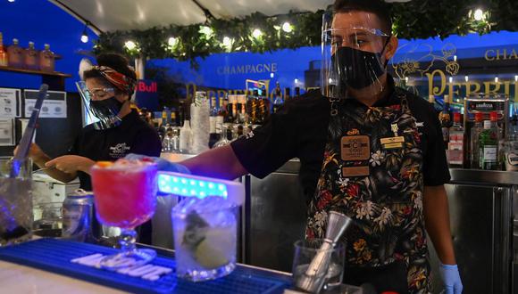 Un barman desinfecta el vaso de una bebida en un restaurante durante su reapertura después de que el gobierno de Panamá relajó las medidas de confinamiento para combatir la pandemia del coronavirus, el 28 de septiembre de 2020. (Luis ACOSTA / AFP).