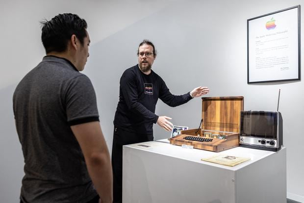 A museum guide presents a replica of an Apple 1 computer to visitors.  (Photo: AFP)