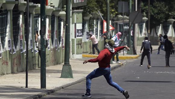 Un estudiante de Ayotzinapa arroja una piedra al Campamento Militar 1 durante una manifestación para exigir la extradición de un funcionario mexicano investigado por la desaparición de 43 estudiantes en 2014, en la Ciudad de México, el 23 de septiembre de 2022. (Foto de ALFREDO ESTRELLA / AFP )