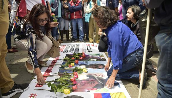 Amigos del periodista Javier Ortega, de 32 años, del fotógrafo Paúl Rivas, de 45, y del conductor Efraín Ortega, de 60, llevaron flores a sus retratos durante una manifestación en Ecuador. (Foto: AFP/Rodrigo Buendía)
