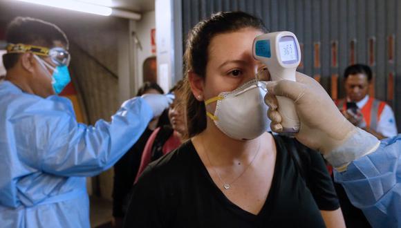 Personal médico controlando la temperatura de los pasajeros a su llegada al Aeropuerto Internacional Jorge Chávez en un vuelo desde España el 11 de marzo de 2020. (Foto de KAREL NAVARRO / Ministerio de Salud de Perú / AFP)