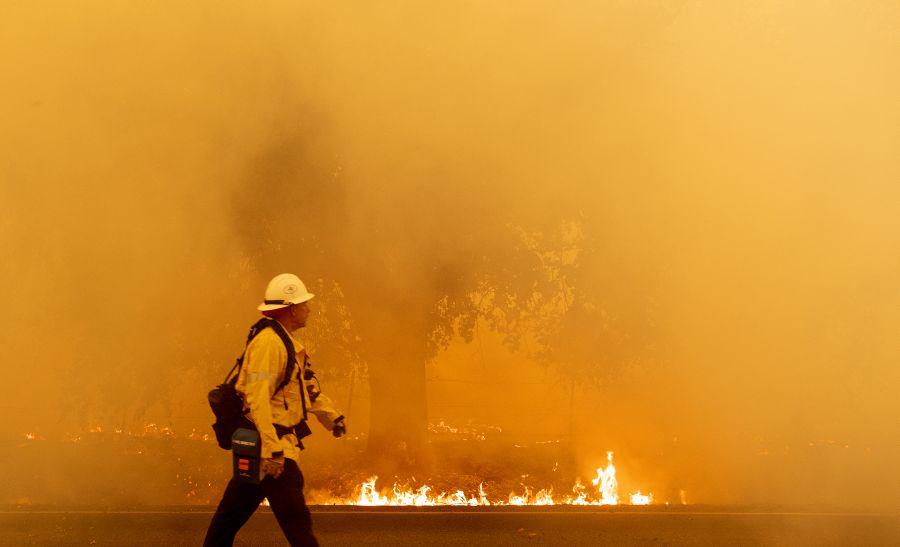 Un bombero de Pacific Gas and Electric camina por una carretera mientras las llamas se acercan en Fairfield, California. (Foto de JOSH EDELSON / AFP).