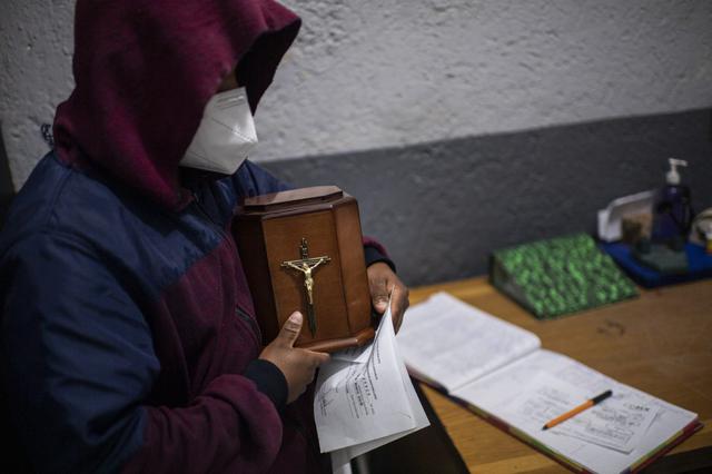 Un hombre recibe la urna que contiene las cenizas de su padre, víctima de COVID-19, en el crematorio del panteón Iztapalapa, en la Ciudad de México. (Pedro PARDO / AFP)