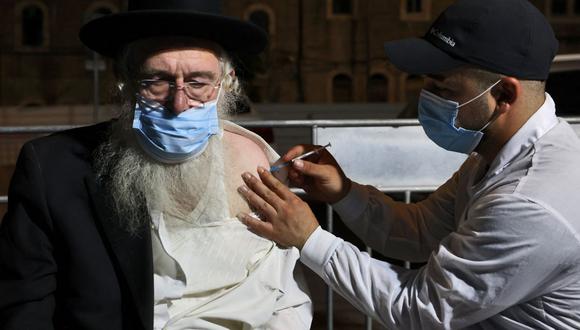 Un trabajador de la salud administra una tercera dosis de la vacuna Pfizer-BioNtech Covid-19 a un hombre en un barrio religioso en Jerusalén, Israel, el 19 de agosto de 2021. (AHMAD GHARABLI / AFP).