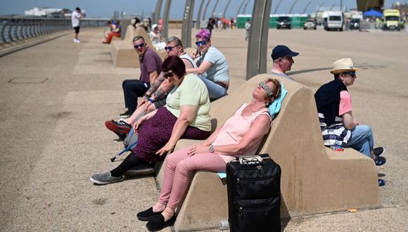 La gente permanece en el paseo marítimo de Blackpool, en el noroeste de Inglaterra, el 17 de julio de 2022. (OLI BUFANDA / AFP).