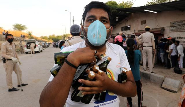 Personas con máscaras de protección son vistas después de comprar alcohol en Nueva Delhi, India. (EFE/EPA/RAJAT GUPTA).