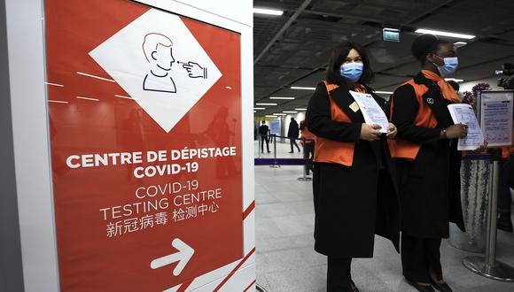 El personal del aeropuerto espera a los pasajeros que vienen de China frente a un área de prueba de COVID-19 establecida en el aeropuerto Roissy Charles de Gaulle, al norte de París, el domingo 1 de enero de 2023. (AP/Aurelien Morissard)