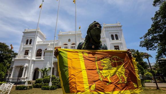 Un manifestante posa con una bandera nacional de Sri Lanka mientras se prepara para abandonar la oficina del Primer Ministro en Colombo, el 14 de julio de 2022. (EFE/EPA/CHAMILA KARUNARATHNE).