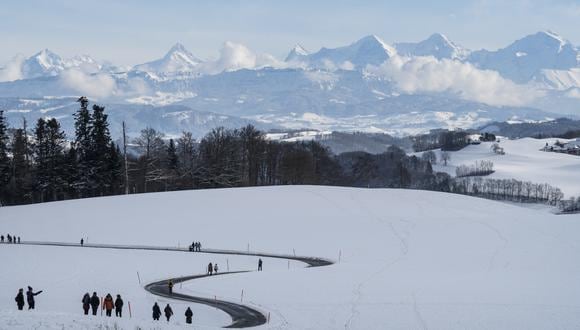 La gente da un paseo por la nieve en la colina Gurten cerca, con los Alpes berneses al fondo, en Berna, Suiza, el 19 de enero de 2023. (Foto de EFE/EPA/CHRISTIAN BEUTLER)