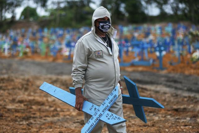 El brasileño Ulisses Xavier, de 52 años, que ha trabajado durante 16 años en el cementerio de Nossa Senhora en Manaus, Brasil, se prepara para colocar cruces en las tumbas durante su turno del 8 de mayo de 2020, en medio de la nueva pandemia de coronavirus. (MICHAEL DANTAS / AFP).