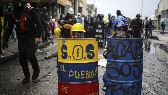 En esta imagen del 9 de junio de 2021, manifestantes antigubernamentales se resguardan detrás de escudos de fabricación casera durante enfrentamientos con la policía en Bogotá. (Foto de archivo: AP/Iván Valencia)