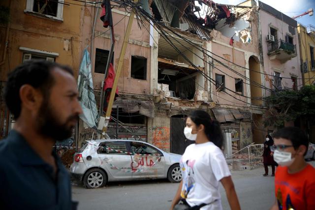 La gente pasa este jueves 13 de agosto de 2020 junto a edificios dañados en el barrio de Mar Mikhael de Beirut (Líbano). (AFP / PATRICK BAZ).