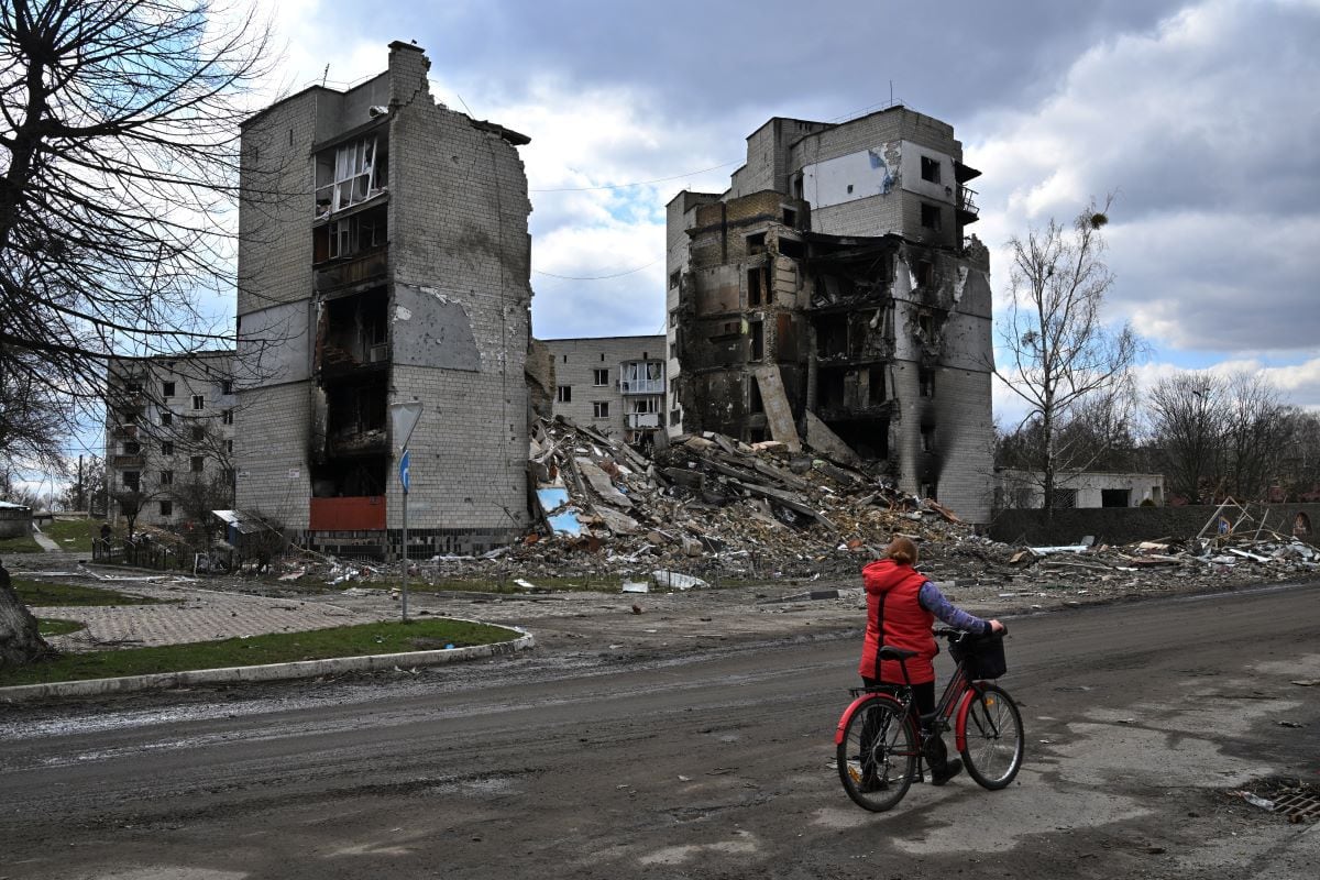 A woman carries her bicycle in front of destroyed buildings in the city of Borodianka, northwest of kyiv, on April 4, 2022. (Sergei SUPINSKY / AFP)