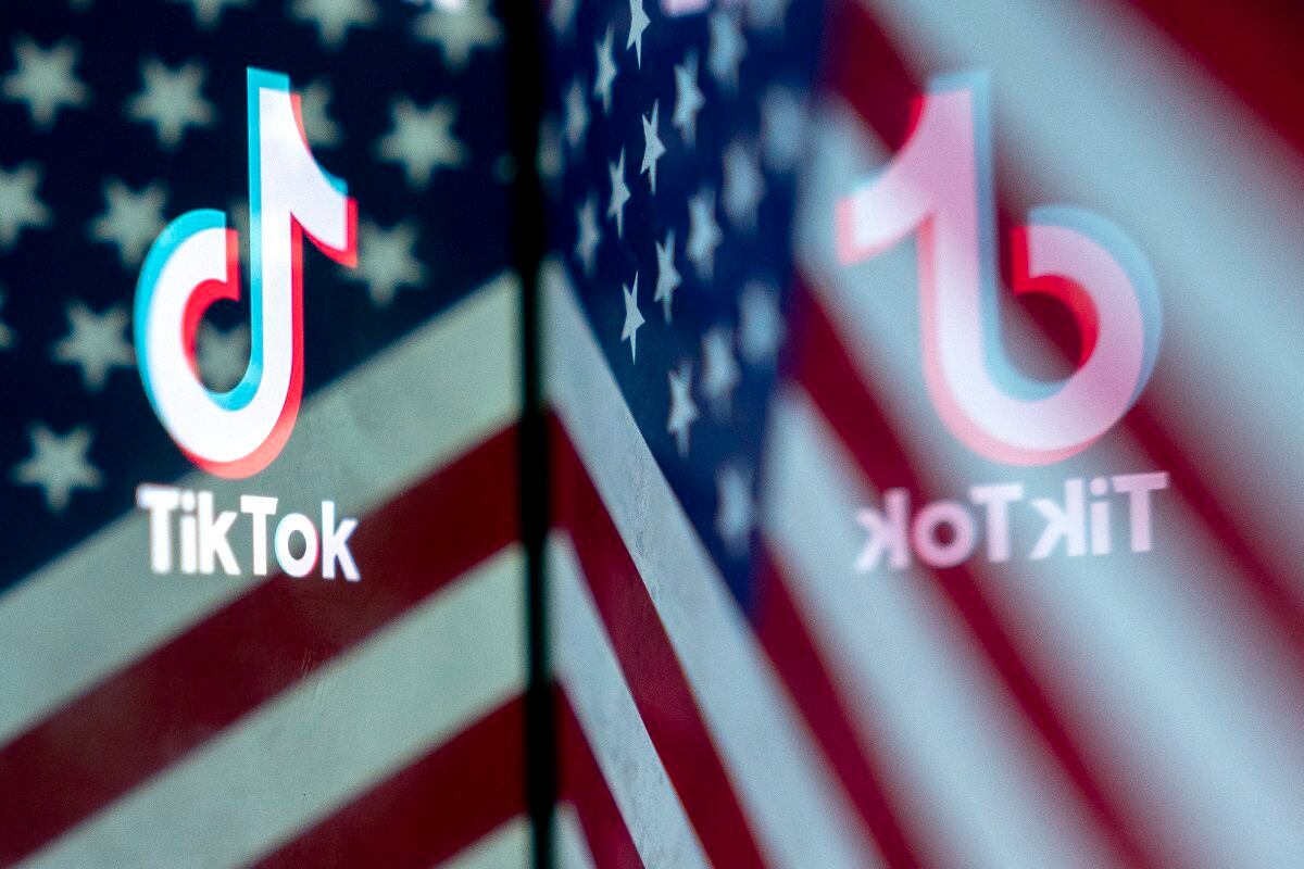 The TikTok logo reflected in an image of the United States flag.  (Photo by Stefani Reynolds/AFP)