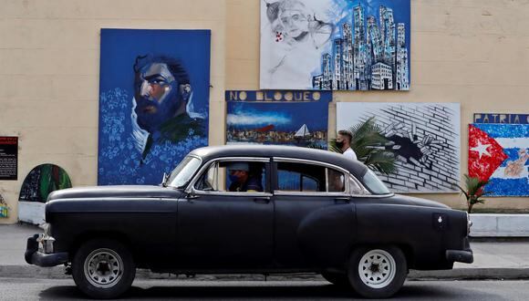 Fotografía de un vehículo mientras cruza frente a pinturas en una calle con consignas e imágenes de líderes de la revolución de Cuba en La Habana. (EFE/ Ernesto Mastrascusa).