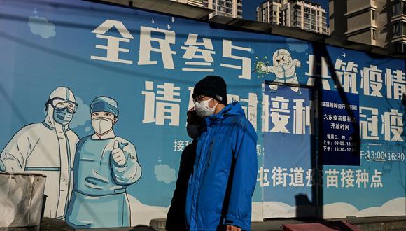Personas con mascarillas faciales caminan por una calle de Beijing, China, el 11 de diciembre de 2022, en plena pandemia de coronavirus. (Noel CELIS / AFP).