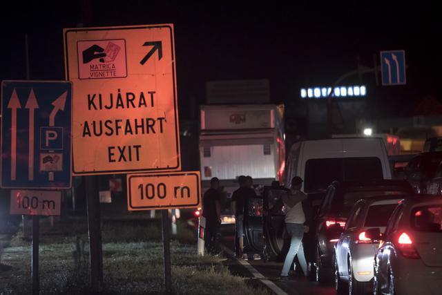 La gente se para junto a sus carros mientras hacen una fila para cruzar la frontera entre Austria y Hungría. (EFE / EPA / CHRISTIAN BRUNA).