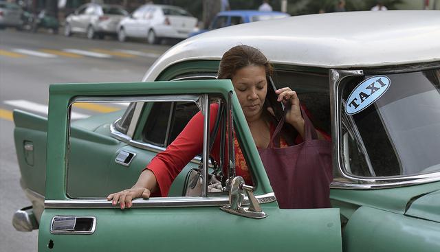 Una cubana sube a un viejo automóvil americano que funge de taxi en una calle de La Habana. (AFP)