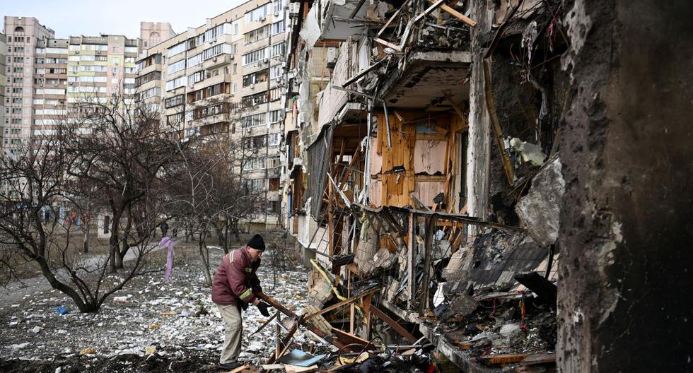 Un hombre limpia los escombros de un edificio residencial dañado en la calle Koshytsa, un suburbio de la capital ucraniana, Kiev, donde supuestamente cayó un proyectil militar, el 25 de febrero de 2022. (Foto: Daniel LEAL / AFP)