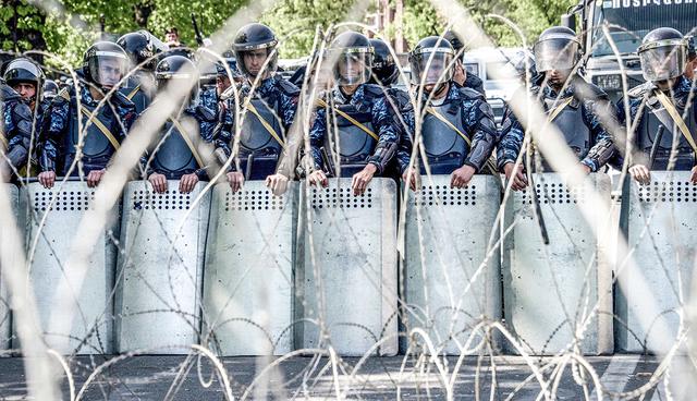 TOPSHOT - Armenian special police forces block a street during an opposition rally in central Yerevan on April 17, 2018, as parliament is expected to elect the country's ex-president as prime minister under a new parliamentary system of government. Opposition demonstrators blockaded government buildings in Armenia's capital on April 17 as parliament was set to confirm the pro-Moscow former president as the real power in the country. / AFP / KAREN MINASYAN