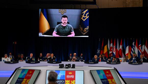 El presidente de Ucrania, Volodymyr Zelensky, aparece en una pantalla gigante mientras pronuncia una declaración en la cumbre de la OTAN en el centro de congresos de Ifema en Madrid, el 29 de junio de 2022. (Foto de GABRIEL BOUYS / AFP).