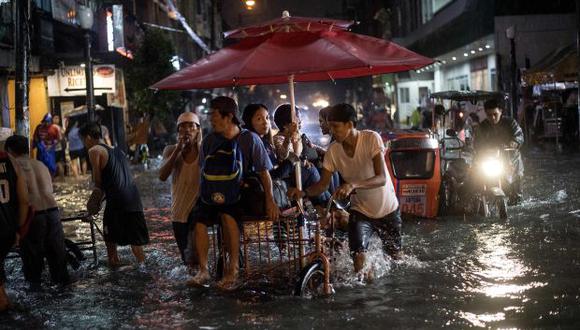 Conductor de Rickshaw que transportaba pasajeros en una calle inundada debido a un fuerte aguacero provocado por la tormenta tropical Yagi cuando abandona el área de responsabilidad filipina, en Manila. (Foto: AFP)