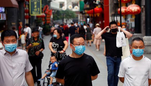 Las personas usan máscaras protectoras mientras caminan en una calle comercial luego del brote de la enfermedad por coronavirus (COVID 19) en una parte histórica de Beijing, China. (Foto: REUTERS / Thomas Peter).
