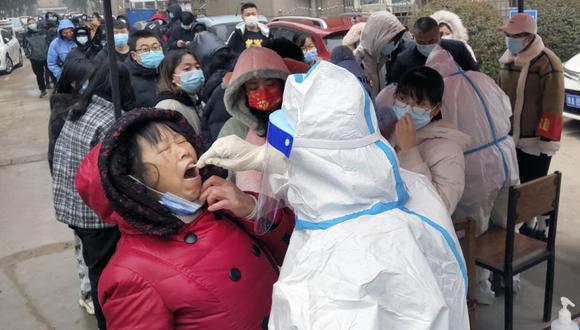 Un trabajador médico que usa un traje protector toma muestras de hisopos para la prueba de COVID-19 a los residentes del condado de Huaxian, en la provincia de Henan, en el centro de China. (Foto: Chinatopix vía AP)