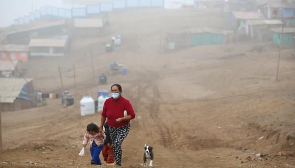 Flor Vera camina entre la neblina con dos de sus seis hijos y su mascota, en el asentamiento humano 6 de Enero. Ella ahora vende tamales entre sus vecinos para subsistir. (Foto: Hugo Curotto/GEC)