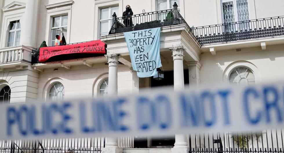Un grupo de ocupantes ilegales muestra pancartas y una bandera nacional de Ucrania en la mansión del oligarca ruso Oleg Deripaska en Belgrave Square, en el centro de Londres, el 14 de marzo de 2022. (TOLGA AKMEN / AFP).