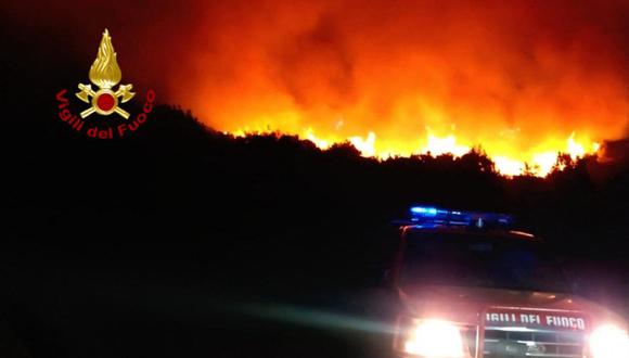 Esta fotografía tomada el 12 de agosto de 2021 por los bomberos de Italia los muestra combatiendo un gran incendio forestal. (Foto: AFP).