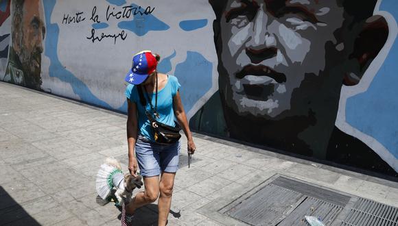 Una mujer camina al lado de un mural de Hugo Chávez y Fidel Castro. (Foto: AP)