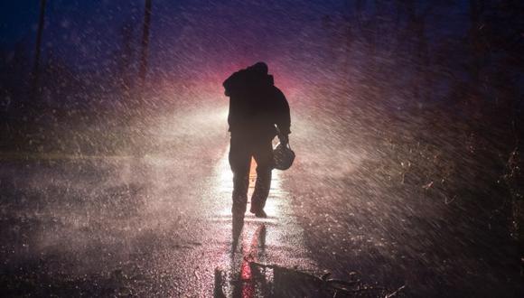 El jefe de bomberos de Montegut, Toby Henry, regresa a su camión de bomberos bajo la lluvia mientras los bomberos cortan árboles en la carretera en Bourg, Louisiana, mientras pasa el huracán Ida. (Foto: Mark Felix / AFP).
