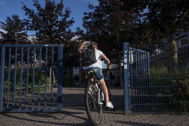 Un estudiante ingresa en su bicicleta en la escuela Christophorusschule, en Rostock, mientras la escuela se reanuda sus clases después de las vacaciones de verano. (John MACDOUGALL / AFP)