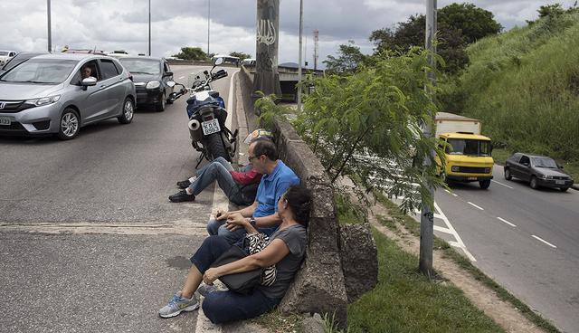 Motorists drive against the flow of traffic as other commuters take cover against a median barrier during a confrontation between police and suspected drug traffickers along the road known as the Linha Amarela, or Yellow Line, in Rio de Janeiro, Brazil, Wednesday, Jan. 31, 2018. A firefight apparently spilled onto the multiple-lane road in northern Rio during a police operation in City of God, a violent shantytown that was featured in 2002 Oscar-nominated film by the same name. (AP Photo/Leo Correa)