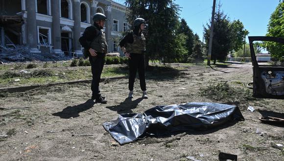 Oficiales de policía ucranianos junto al cuerpo de una víctima que yacía dentro de una bolsa para cadáveres después de un ataque ruso en la aldea de Zolochiv, región de Kharkiv, el 1 de mayo de 2024. (Foto de SERGEY BOBOK / AFP).