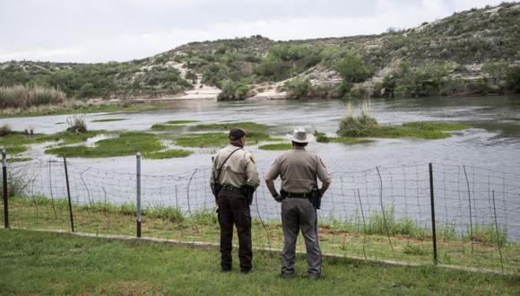 Un par de oficiales miran hacia el Río Bravo entre México y los Estados Unidos en Del Rio, Texas. (Foto: Sergio FLORES / AFP).